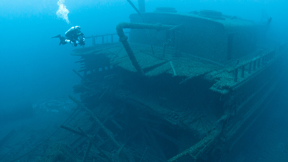 a scuba diver next to a shipwreck underwater
